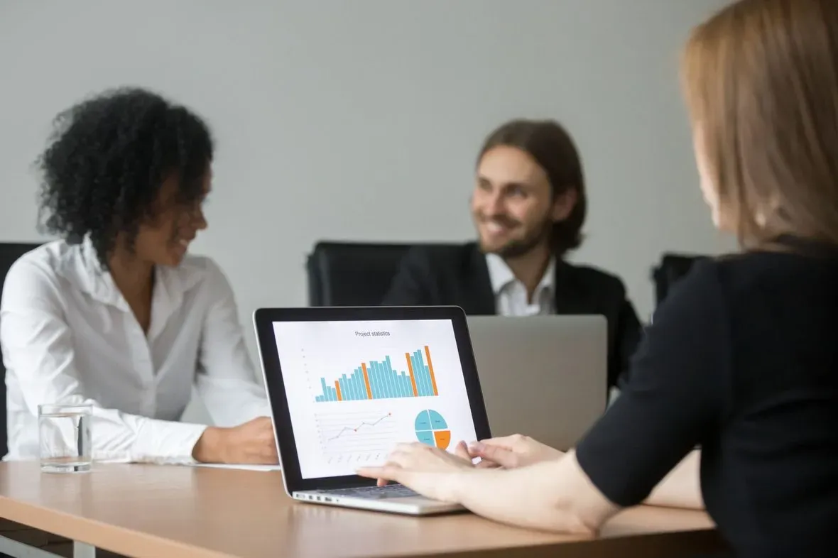 Equipe comercial diversa analisando estatísticas de projeto em reunião no escritório